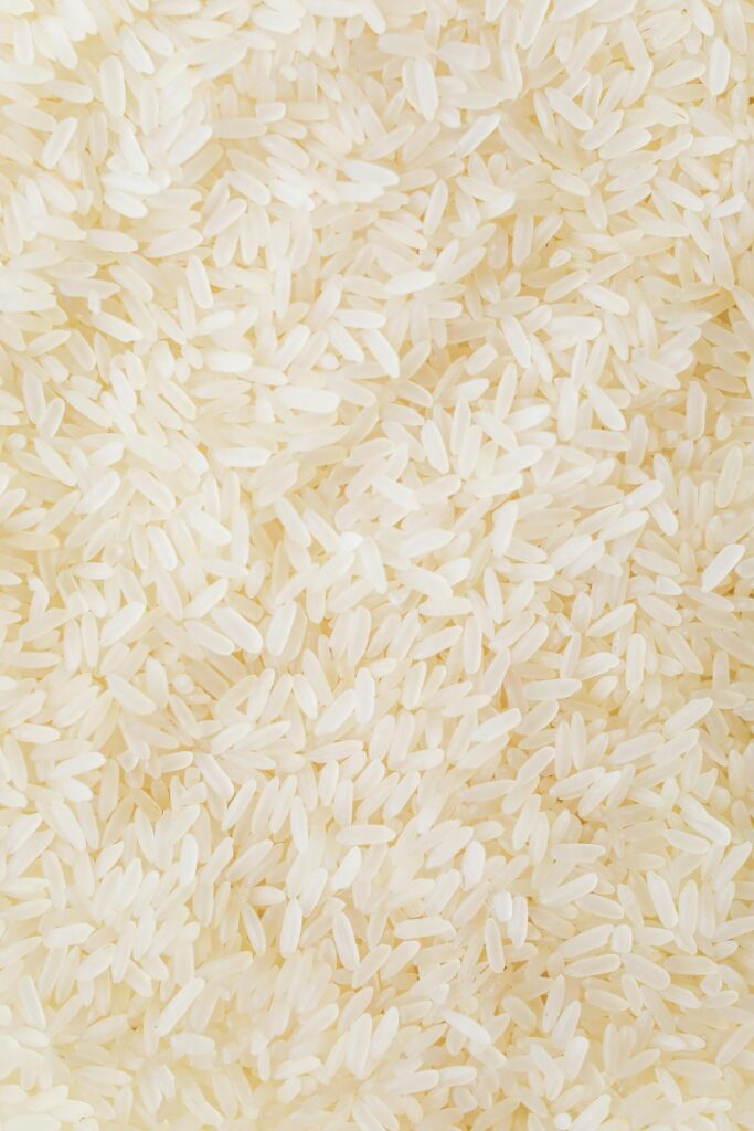 Close-up image of numerous white rice grains, showcasing texture and abundance.